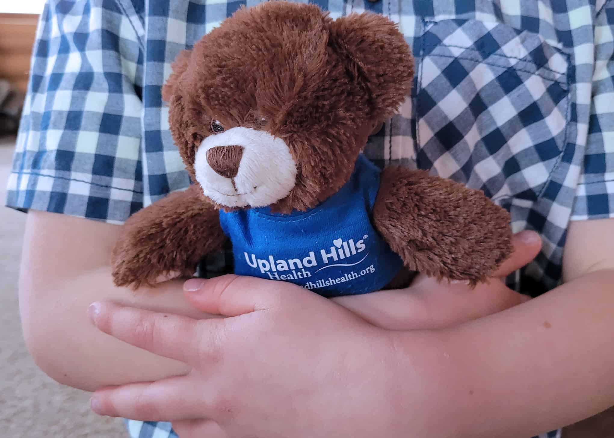 child holding an Upland Hills Health teddy bear